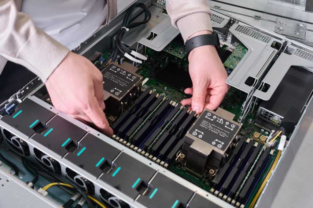 Technician inserts memory modules into a server motherboard inside an open chassis.